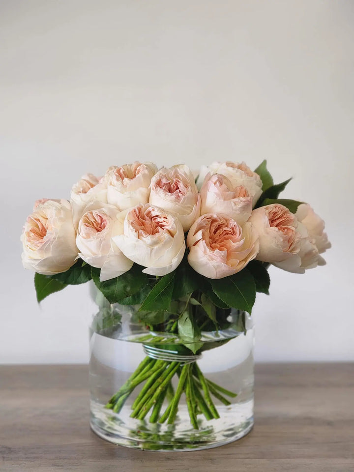 a tight modern david austin juliet garden rose arrangement in a clear glass bowl